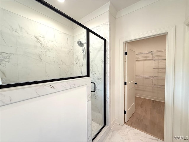 bathroom with a marble finish shower, a spacious closet, and marble finish floor