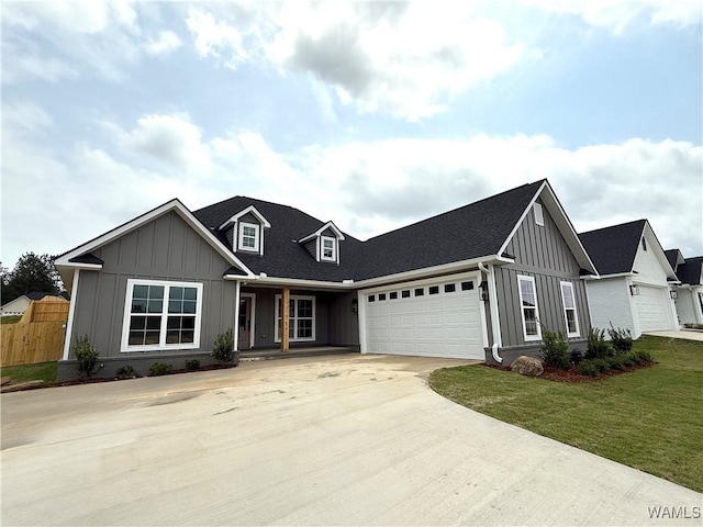 view of front of house with concrete driveway, board and batten siding, a porch, a front yard, and a garage