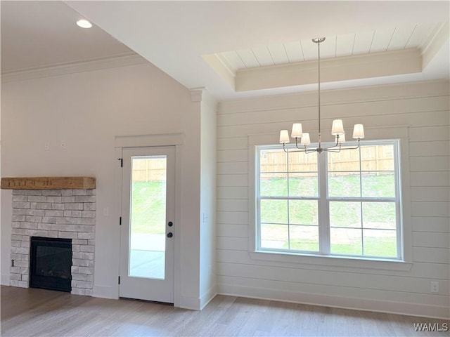 doorway to outside with a tray ceiling, light wood-style floors, plenty of natural light, and ornamental molding
