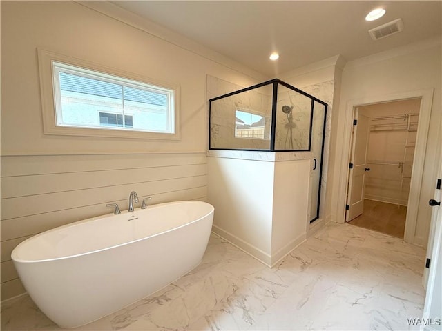 bathroom with a spacious closet, a soaking tub, visible vents, and a stall shower