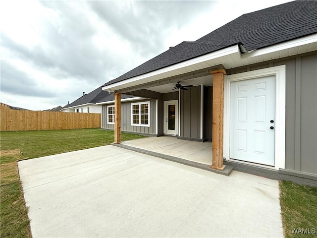 back of house with ceiling fan, roof with shingles, fence, and a lawn