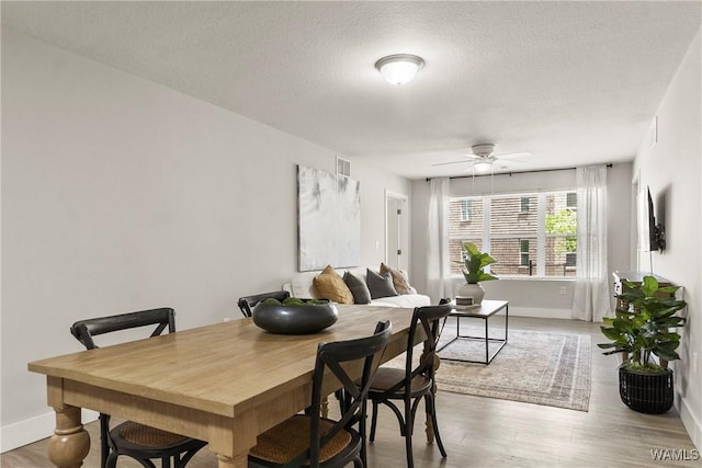 dining space featuring ceiling fan, light hardwood / wood-style floors, and a textured ceiling