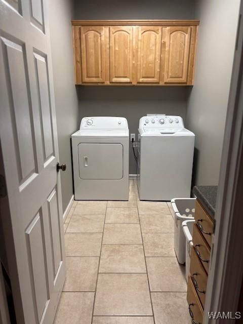 clothes washing area featuring independent washer and dryer, light tile patterned floors, and cabinet space