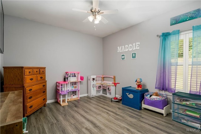 recreation room featuring baseboards, a ceiling fan, and wood finished floors