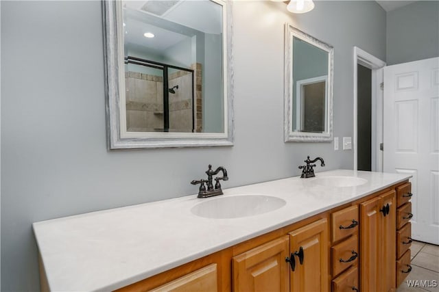 bathroom with tile patterned flooring, a sink, double vanity, and a tile shower
