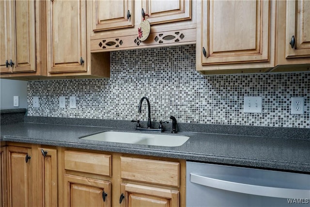kitchen featuring backsplash, dark countertops, dishwasher, and a sink