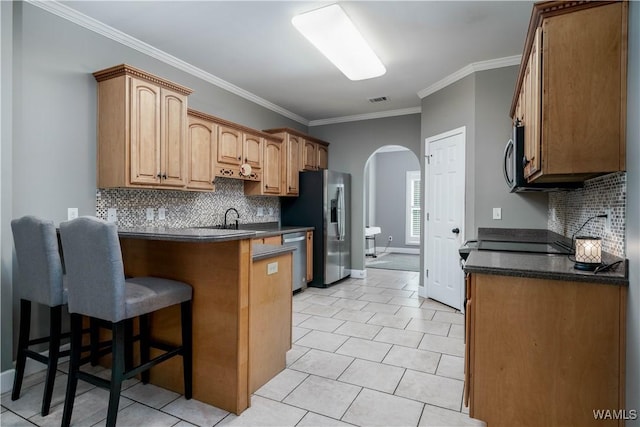 kitchen with a peninsula, stainless steel appliances, a kitchen breakfast bar, arched walkways, and dark countertops