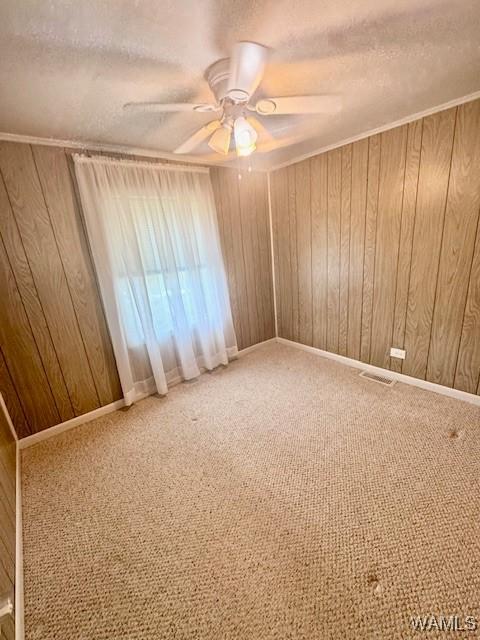 1511 Service St, Demopolis, AL 36732 - spare room with a textured ceiling, wood walls, ceiling fan, and carpet flooring