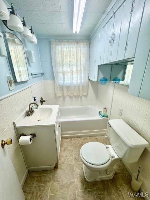 1511 Service St, Demopolis, AL 36732 - full bath with toilet, tile walls, a bathtub, vanity, and wainscoting