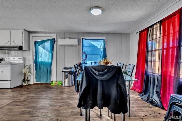 dining area with a wall mounted air conditioner, plenty of natural light, a textured ceiling, and wood finished floors