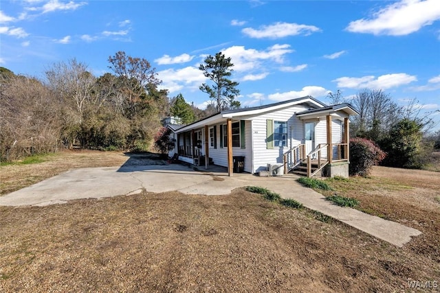 view of side of home with covered porch and a lawn