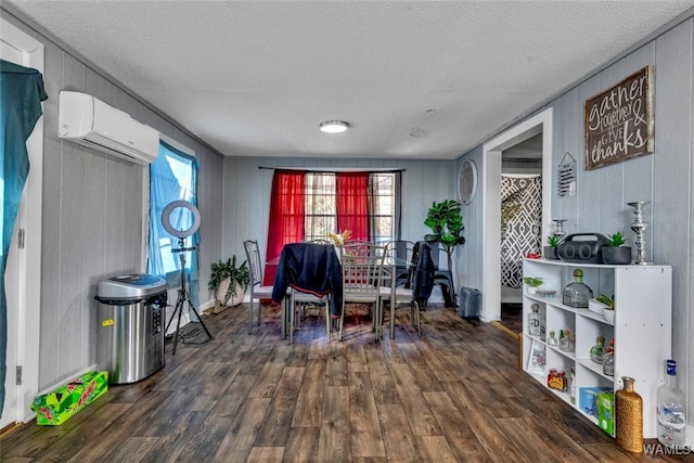 sitting room featuring dark wood-type flooring, a textured ceiling, and a wall mounted AC