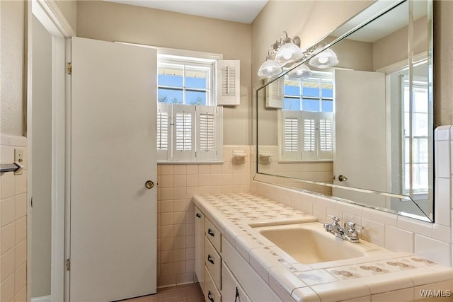 bathroom featuring a wainscoted wall, tile walls, a healthy amount of sunlight, and vanity