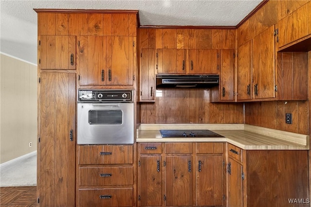 kitchen featuring under cabinet range hood, brown cabinets, black electric stovetop, and stainless steel oven