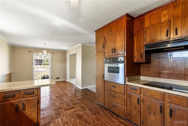 kitchen featuring oven, brown cabinets, and under cabinet range hood