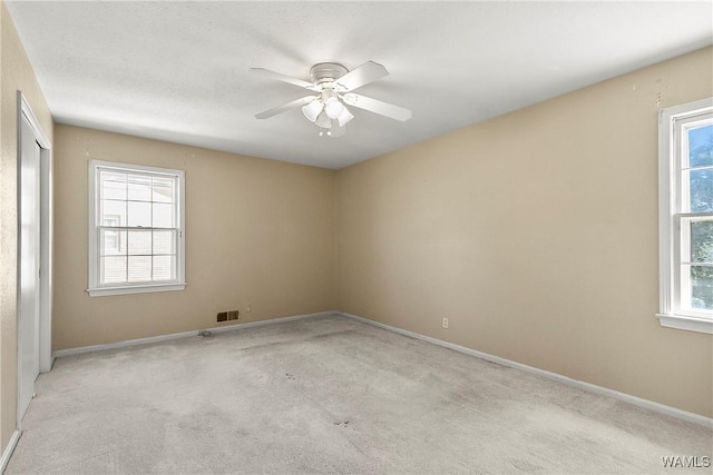 spare room featuring visible vents, baseboards, light colored carpet, and ceiling fan