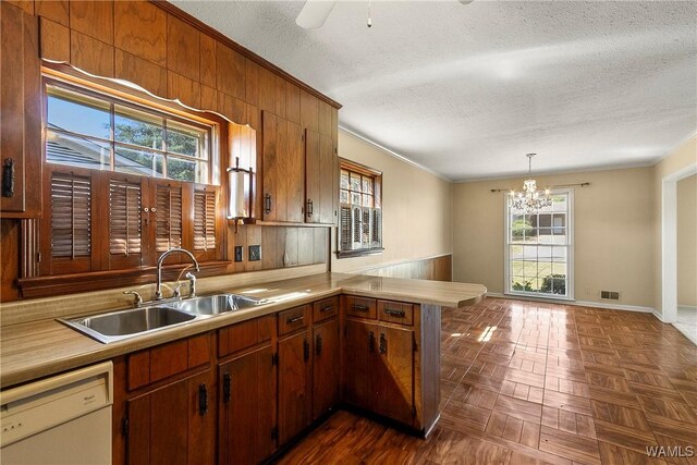 kitchen featuring a sink, a peninsula, white dishwasher, light countertops, and crown molding