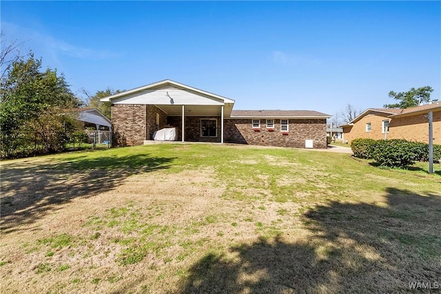 back of property with a yard and brick siding