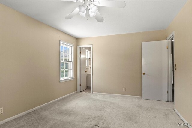 unfurnished bedroom with ensuite bath, a ceiling fan, baseboards, and light carpet