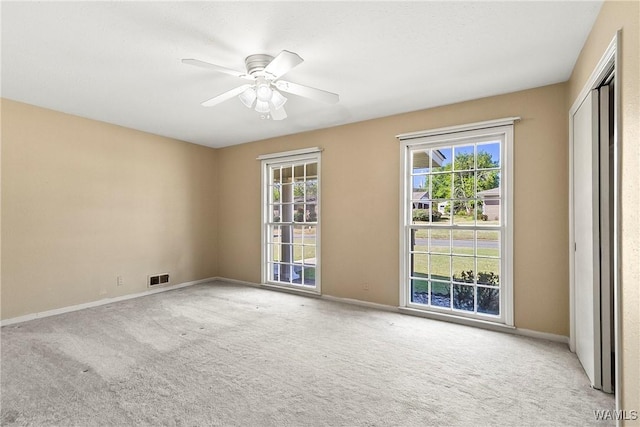 unfurnished room featuring visible vents, carpet floors, baseboards, and a ceiling fan