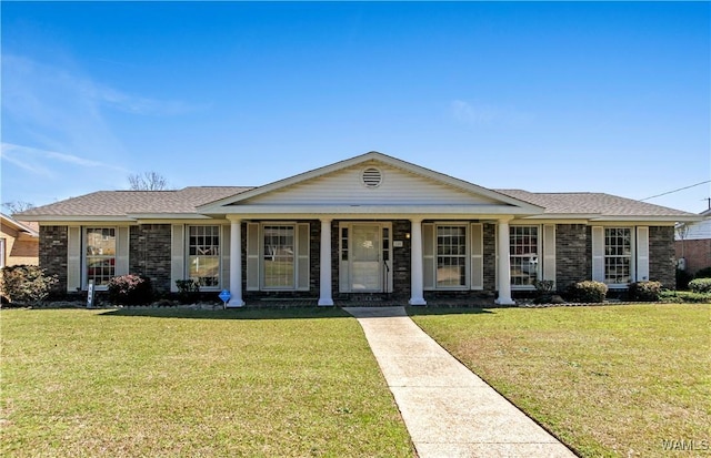 view of front of home featuring brick siding, a porch, a front yard, and roof with shingles