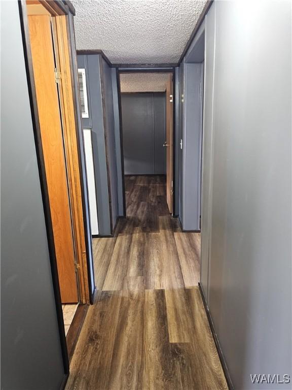 corridor with a textured ceiling and dark hardwood / wood-style floors