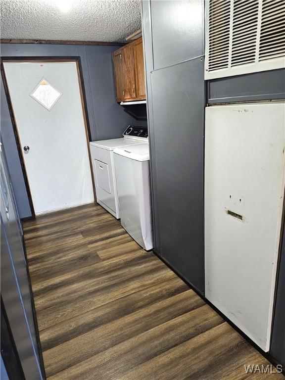 washroom with cabinets, a textured ceiling, dark hardwood / wood-style floors, and washer and dryer