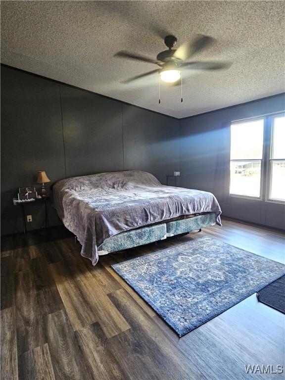 bedroom with hardwood / wood-style flooring, ceiling fan, and a textured ceiling