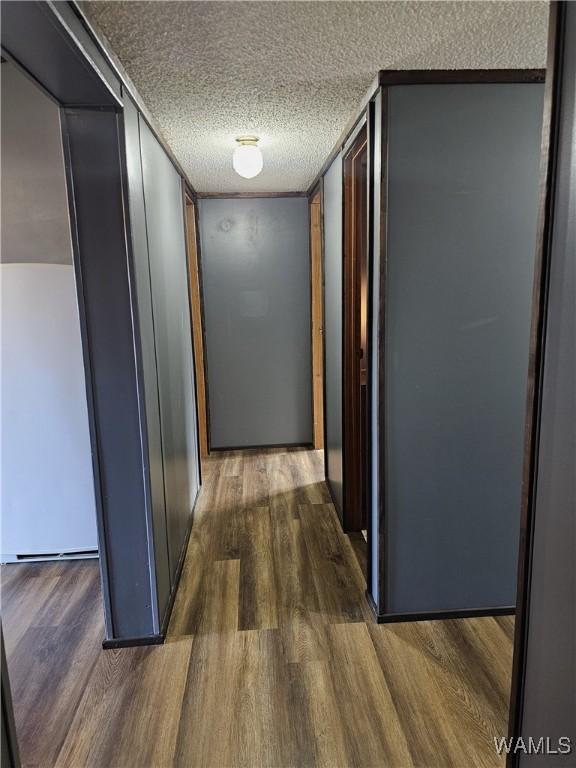 corridor with dark hardwood / wood-style floors and a textured ceiling