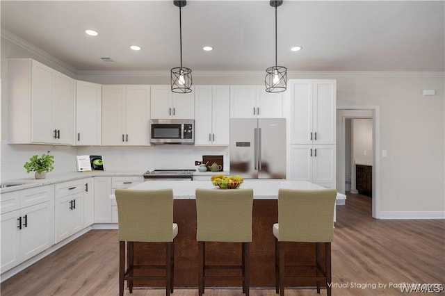 kitchen featuring a kitchen breakfast bar, pendant lighting, white cabinetry, a center island, and stainless steel appliances