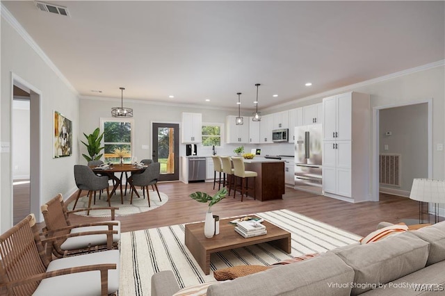 living room featuring sink, wood-type flooring, crown molding, and a chandelier