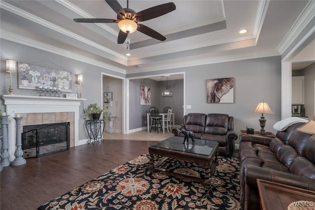 living room with ceiling fan, a raised ceiling, ornamental molding, a fireplace, and hardwood / wood-style flooring