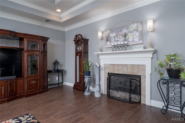 living room featuring a tile fireplace, dark hardwood / wood-style floors, a raised ceiling, and crown molding