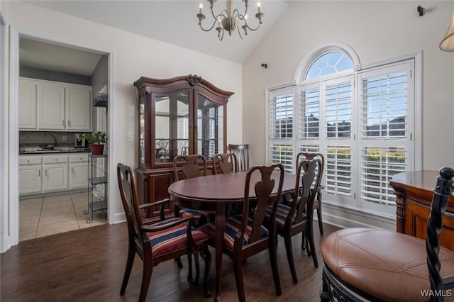 dining space with hardwood / wood-style flooring, lofted ceiling, and an inviting chandelier