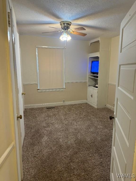 unfurnished bedroom with ceiling fan, carpet flooring, and a textured ceiling