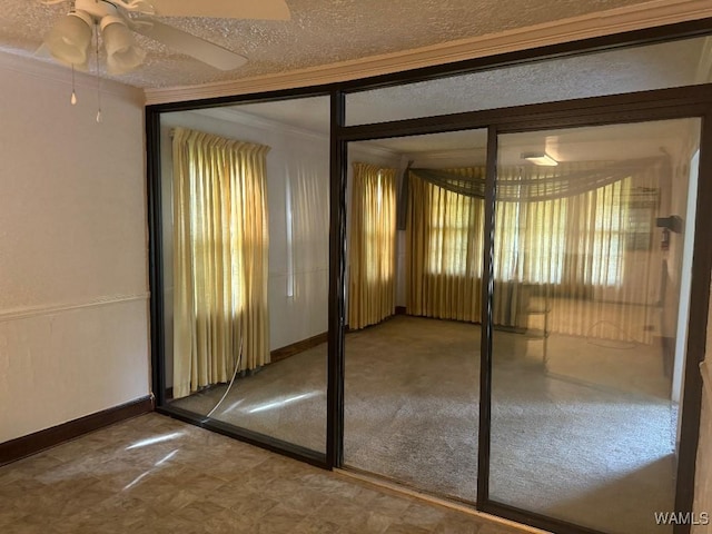 doorway with crown molding, ceiling fan, and a textured ceiling