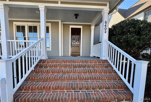 property entrance with covered porch and brick siding