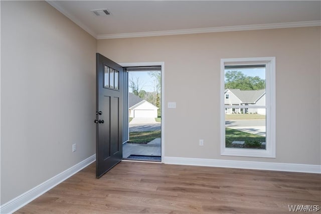 entrance foyer with crown molding, baseboards, light wood finished floors, and visible vents