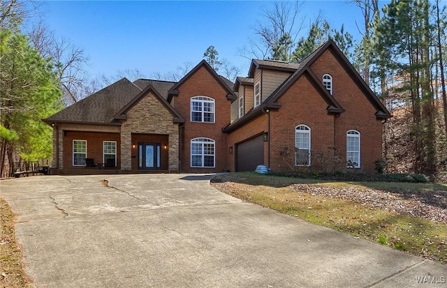 view of front of home featuring an attached garage, stone siding, driveway, and brick siding