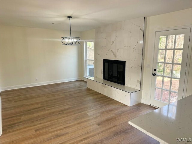 unfurnished living room with hardwood / wood-style flooring, a high end fireplace, and an inviting chandelier