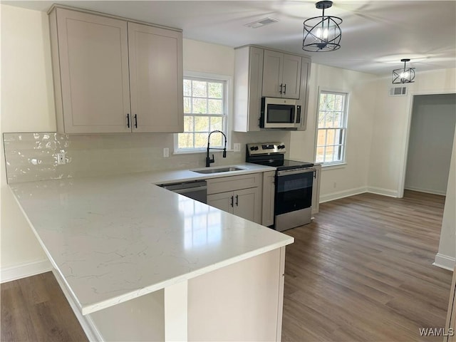 kitchen featuring hanging light fixtures, appliances with stainless steel finishes, sink, and kitchen peninsula