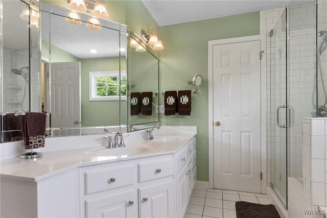 bathroom with a textured ceiling, a shower with shower door, tile patterned floors, and vanity