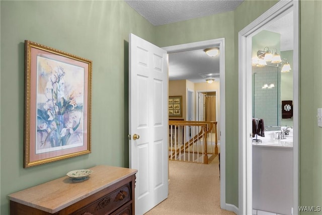 hallway with a textured ceiling, light carpet, and sink