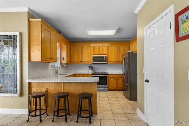 kitchen with a kitchen breakfast bar, stainless steel appliances, kitchen peninsula, light tile patterned floors, and sink