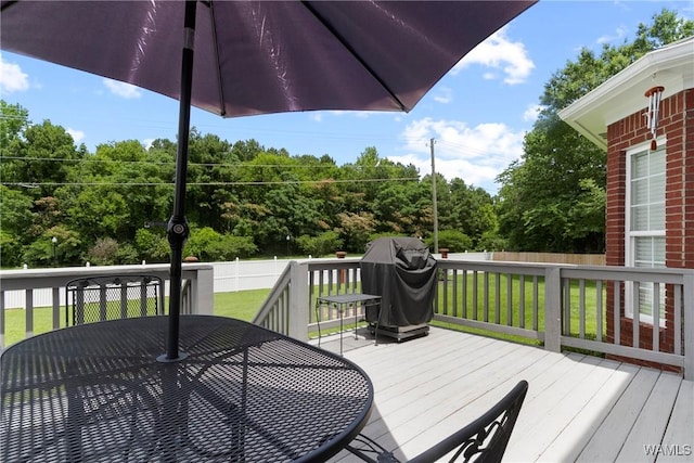 wooden deck featuring a yard and a grill