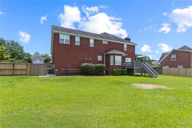 back of property with a yard and a wooden deck