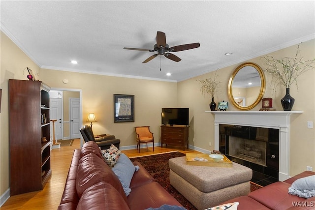 living room featuring ceiling fan, a fireplace, ornamental molding, and hardwood / wood-style flooring