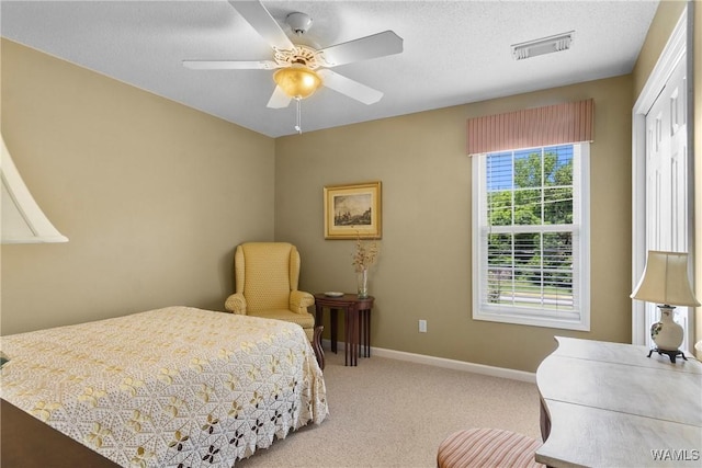 carpeted bedroom with a textured ceiling, ceiling fan, and a closet