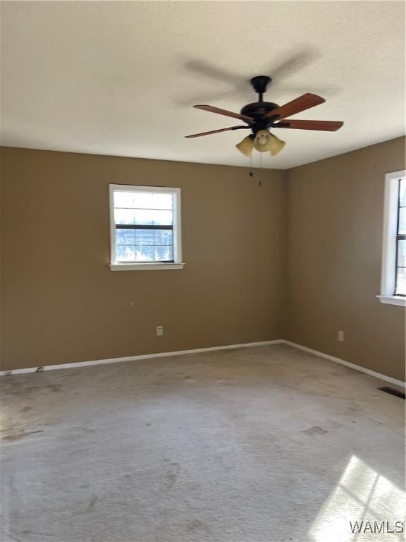 carpeted empty room with ceiling fan and a textured ceiling