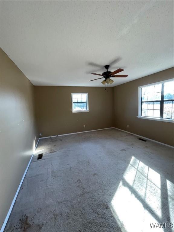 unfurnished living room with a textured ceiling, light colored carpet, ceiling fan, and wood walls